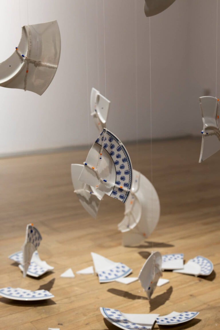 Agathe Dessaux, 300, rue de l’Égalité, 2025, installation, textile et porcelaine, tissage Jacquard, fils de coton, assiettes du service à vaisselle de son enfance, perles de verre. Photo : Annie France Leclerc