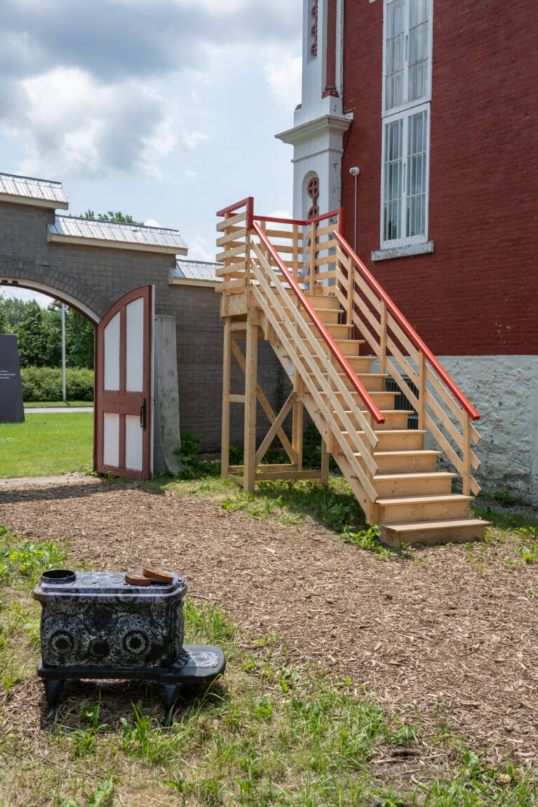 La Famille Plouffe, R’monter en haut!, 2025, installation en nature, poêle à bois, escalier, objets rencontrés et apprivoisés. Photo : Paul Litherland